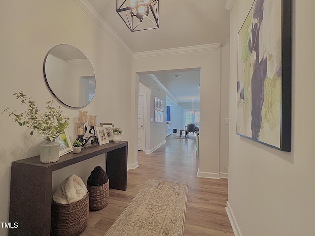 hall with ornamental molding, an inviting chandelier, and light hardwood / wood-style floors