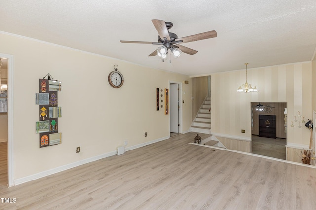 unfurnished living room with ornamental molding, ceiling fan with notable chandelier, a textured ceiling, and light wood-type flooring