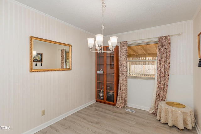 dining room featuring ornamental molding, a chandelier, hardwood / wood-style floors, and a textured ceiling