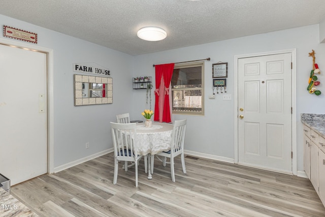 dining room featuring a textured ceiling and light hardwood / wood-style floors