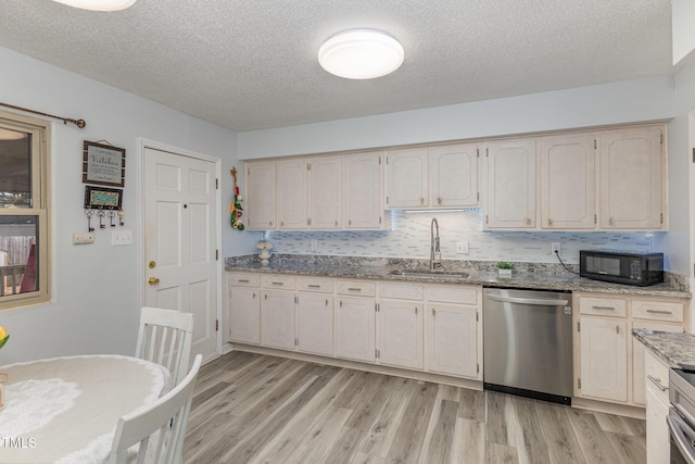 kitchen featuring tasteful backsplash, sink, stainless steel dishwasher, light stone counters, and a textured ceiling