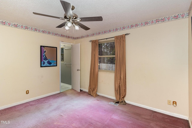 carpeted empty room with ceiling fan and a textured ceiling