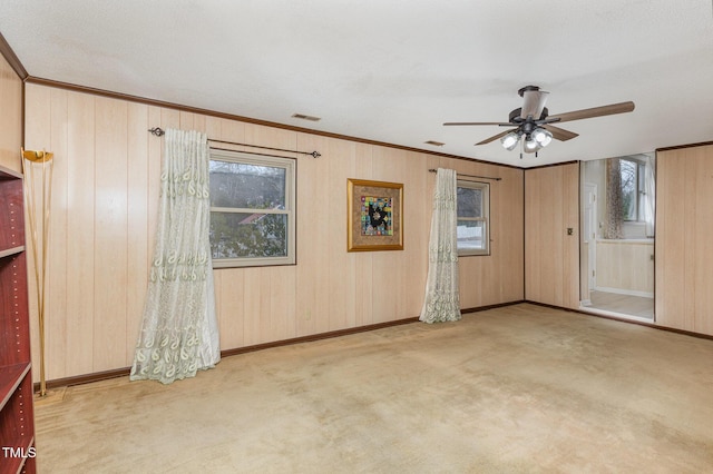 interior space with a healthy amount of sunlight, wooden walls, and light carpet