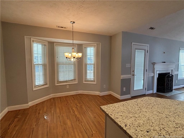 unfurnished dining area featuring a notable chandelier, hardwood / wood-style flooring, and a textured ceiling