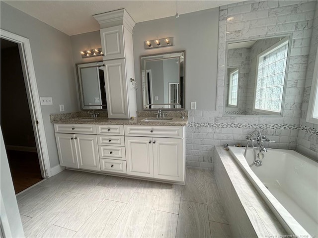 bathroom featuring a relaxing tiled tub and vanity