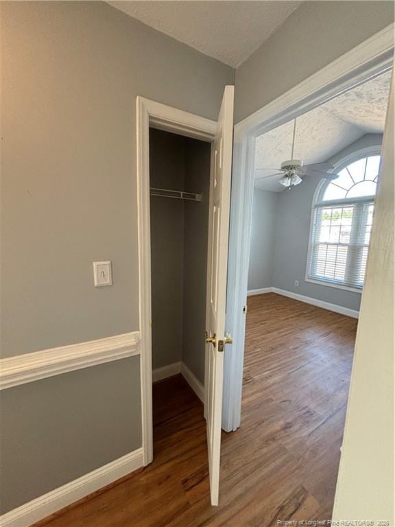 interior space with a closet, vaulted ceiling, a textured ceiling, and wood-type flooring