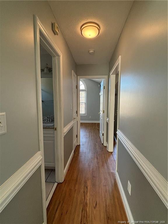 corridor featuring dark wood-type flooring and a textured ceiling