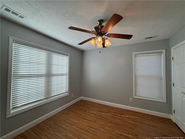 unfurnished room with ceiling fan, a textured ceiling, and dark hardwood / wood-style floors