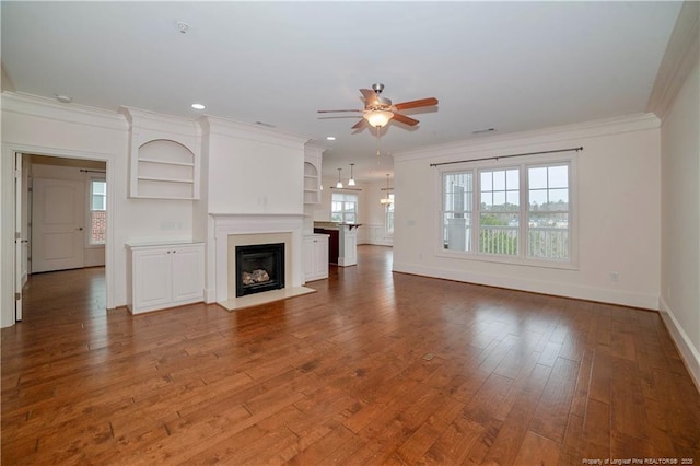 unfurnished living room featuring hardwood / wood-style flooring, ceiling fan, a fireplace, and crown molding