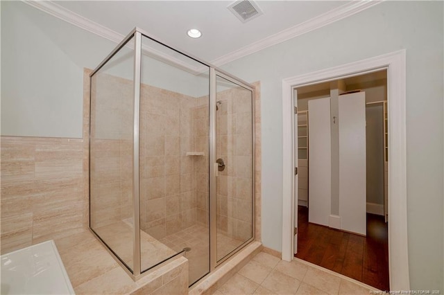 full bathroom with a walk in closet, visible vents, ornamental molding, a shower stall, and tile patterned flooring