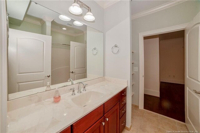 bathroom with crown molding, vanity, baseboards, and tile patterned floors