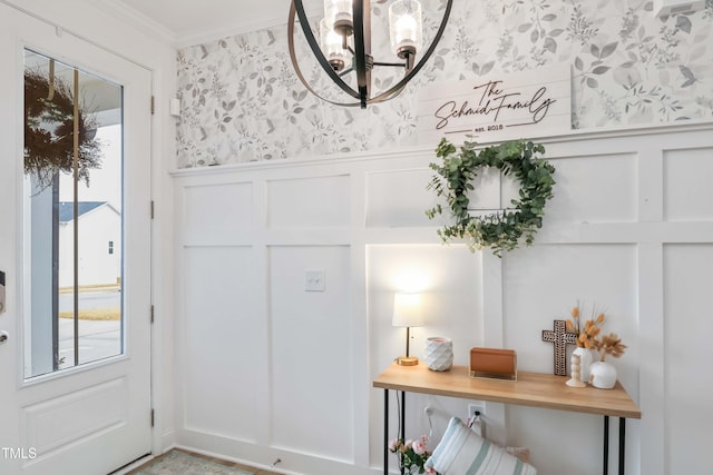 foyer with crown molding and an inviting chandelier