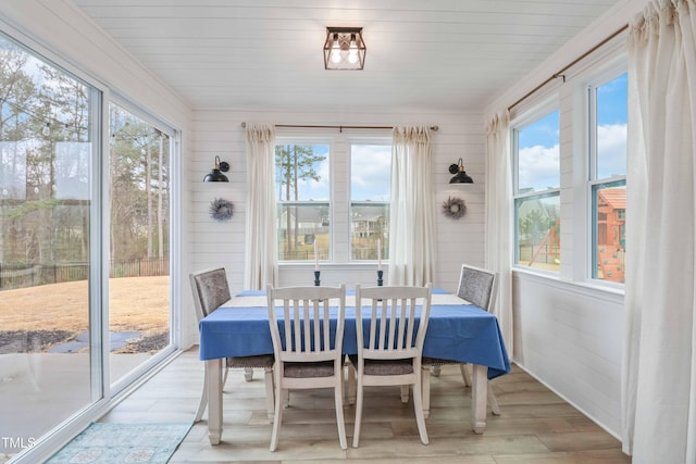 dining space with wooden walls and light wood-type flooring