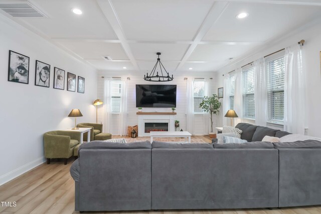 living room with coffered ceiling, beam ceiling, a chandelier, light wood-type flooring, and a fireplace