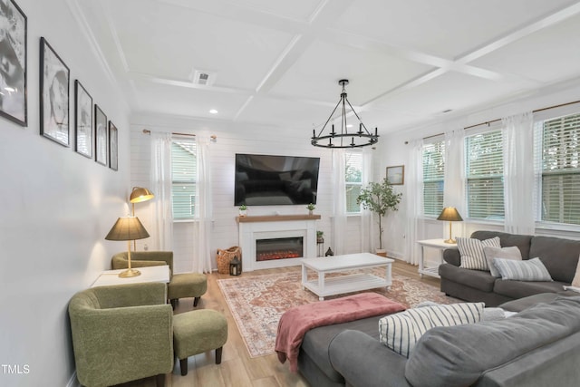 living room with coffered ceiling, a notable chandelier, light hardwood / wood-style floors, and a fireplace