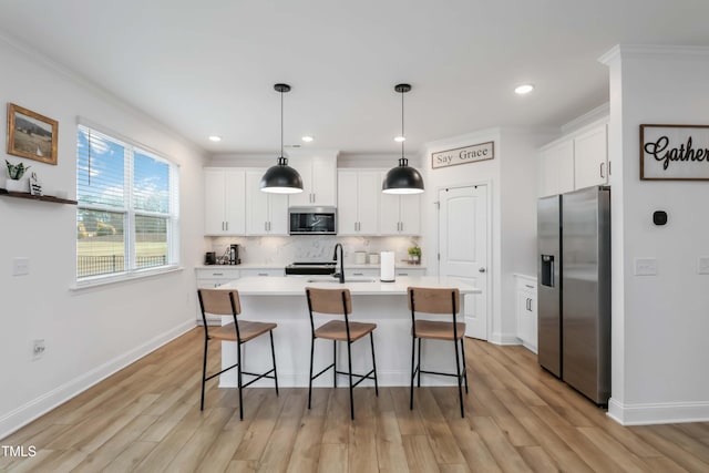 kitchen with pendant lighting, ornamental molding, stainless steel appliances, and white cabinets