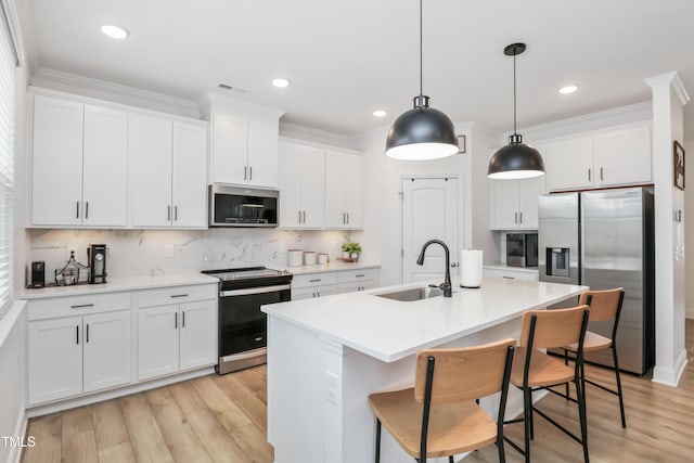 kitchen featuring pendant lighting, appliances with stainless steel finishes, sink, and white cabinets