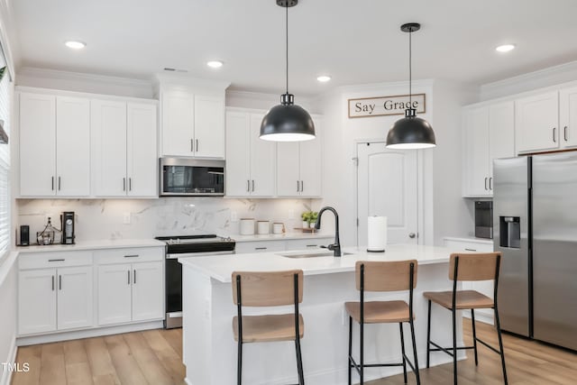 kitchen with white cabinetry, sink, decorative light fixtures, and stainless steel appliances