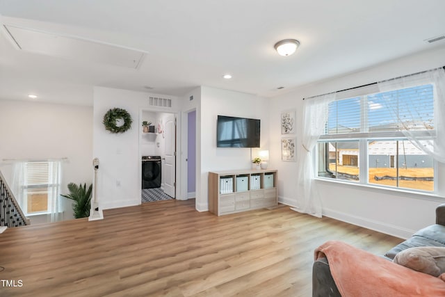 living room with a healthy amount of sunlight, washer / clothes dryer, and light hardwood / wood-style flooring