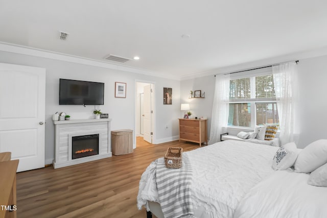 bedroom featuring connected bathroom, crown molding, and wood-type flooring