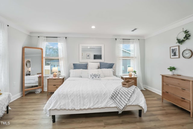 bedroom with multiple windows, crown molding, and hardwood / wood-style floors