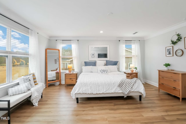 bedroom with ornamental molding, multiple windows, and light wood-type flooring