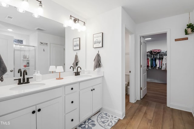 bathroom featuring vanity, hardwood / wood-style floors, a shower with door, and toilet