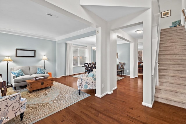 living room featuring dark wood-type flooring, ornamental molding, and a chandelier