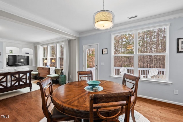 dining space with crown molding and light hardwood / wood-style flooring