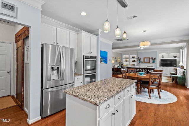 kitchen with white cabinetry, a center island, light stone countertops, appliances with stainless steel finishes, and pendant lighting