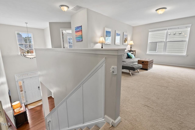 stairs with carpet floors and an inviting chandelier