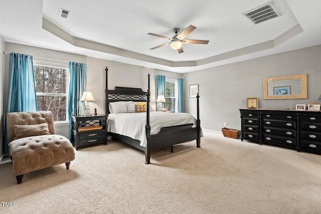 bedroom featuring multiple windows, carpet flooring, ceiling fan, and a raised ceiling