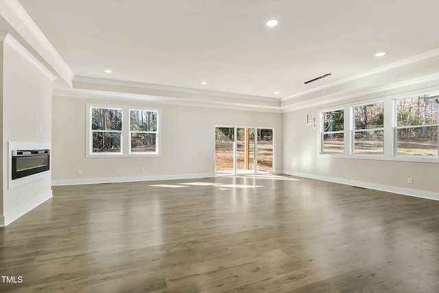 unfurnished living room with dark wood-type flooring, a tray ceiling, and heating unit