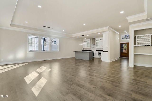 unfurnished living room with crown molding, a tray ceiling, dark hardwood / wood-style flooring, and built in shelves