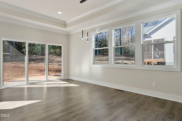 empty room with ornamental molding, a tray ceiling, and dark hardwood / wood-style flooring