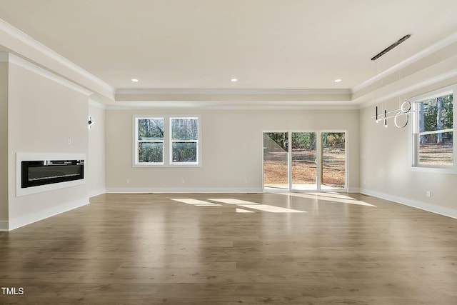 unfurnished living room featuring plenty of natural light and a tray ceiling