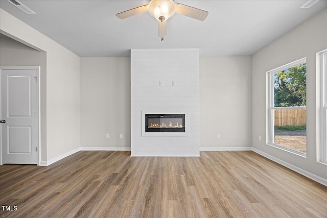 unfurnished living room featuring ceiling fan, a large fireplace, and hardwood / wood-style floors