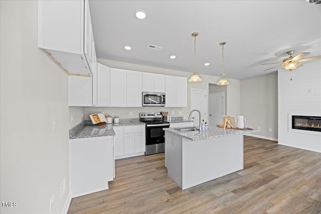 kitchen featuring sink, a center island with sink, pendant lighting, stainless steel appliances, and white cabinets