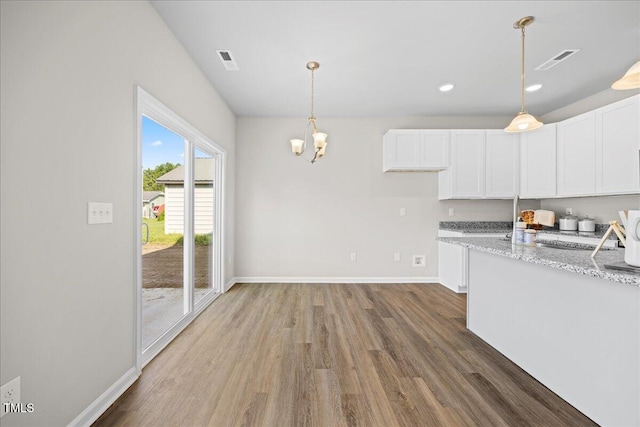 kitchen with light stone countertops, dark wood-type flooring, pendant lighting, and white cabinets