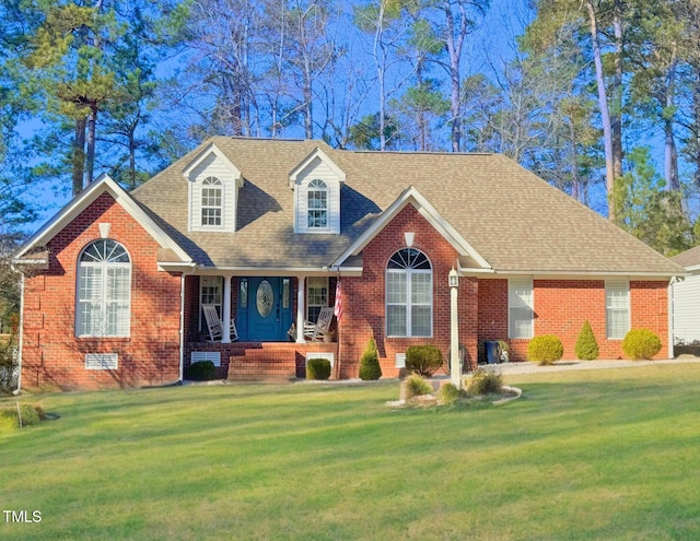 new england style home with roof with shingles, a front lawn, and brick siding