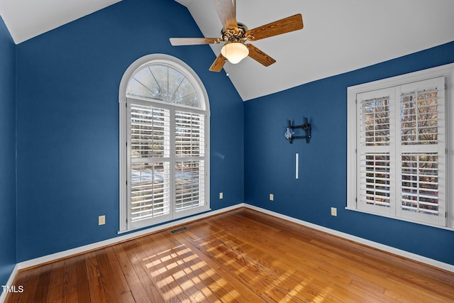 unfurnished room featuring hardwood / wood-style flooring, a ceiling fan, visible vents, vaulted ceiling, and baseboards