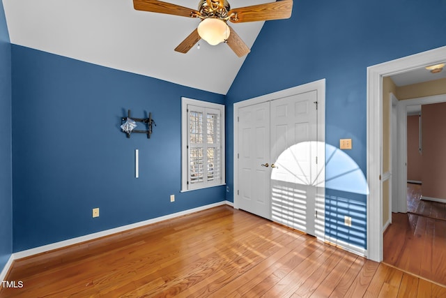 unfurnished bedroom featuring lofted ceiling, wood finished floors, a ceiling fan, baseboards, and a closet