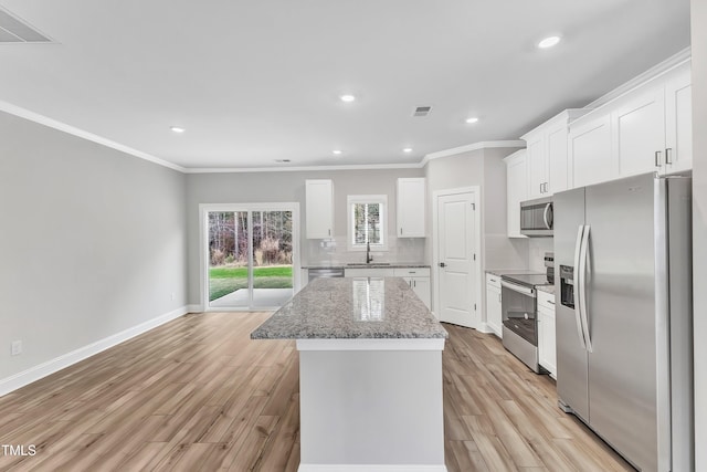 kitchen featuring light stone countertops, white cabinetry, sink, a kitchen island, and stainless steel appliances