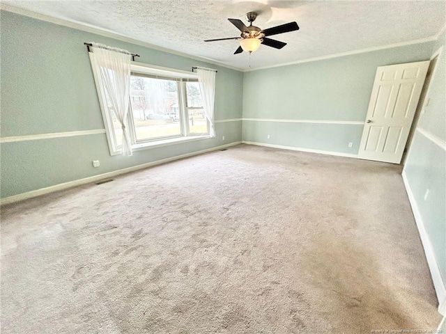 carpeted empty room featuring ceiling fan, crown molding, and a textured ceiling