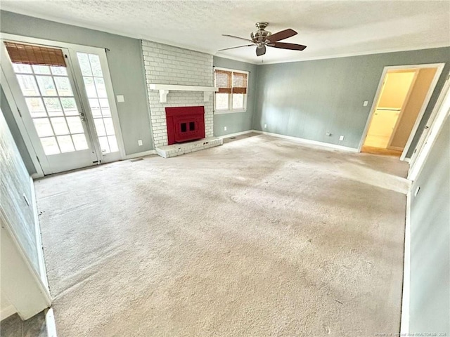 unfurnished living room with ceiling fan, carpet floors, a fireplace, and a textured ceiling