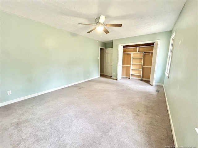 unfurnished bedroom with ceiling fan, light carpet, a textured ceiling, and a closet