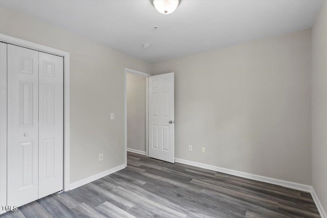 unfurnished bedroom with dark hardwood / wood-style flooring and a closet