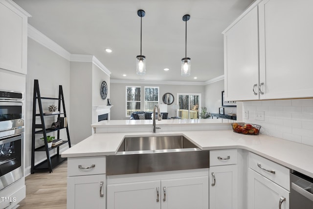 kitchen featuring sink, white cabinetry, hanging light fixtures, kitchen peninsula, and backsplash