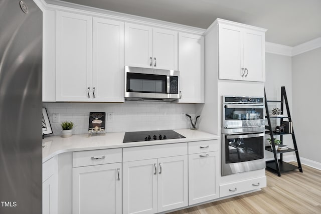 kitchen featuring stainless steel appliances, white cabinetry, backsplash, and light hardwood / wood-style floors