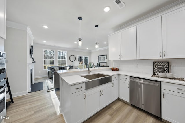 kitchen featuring stainless steel appliances, kitchen peninsula, sink, and white cabinets